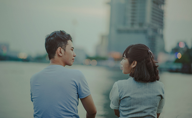 An Asian couple sitting by the water front.