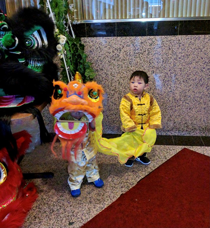 Two young children dressed in a traditional Chinese lion costume.