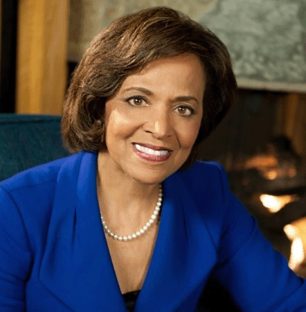 Dr. Yvonne Thompson Maddox wearing a blue blazer, seated in front of a fireplace. 