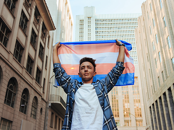 Image of a person holding the Transgender Pride flag above their head.
