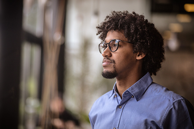 African American professional with glasses staring outside.