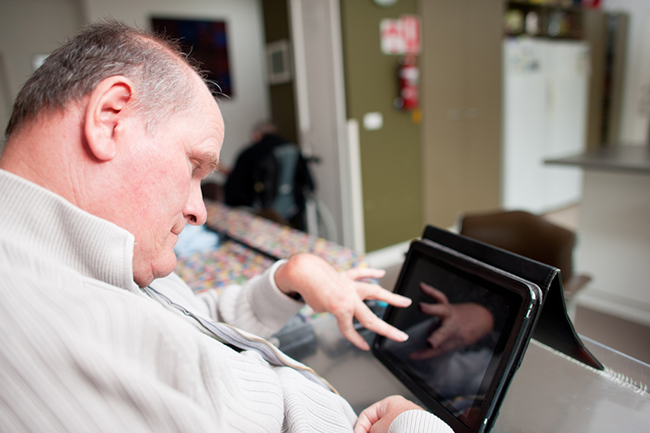 Man with a disability using a tablet device while seated.