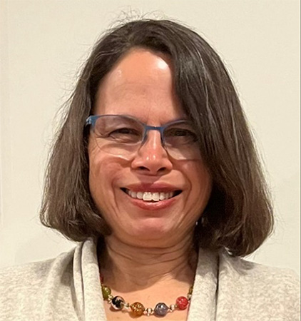Associate professional headshot of the editor of the NIH Record, Dana Talesnik wearing a beige cardigan and beaded necklace.