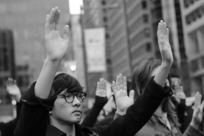 A young asian man protesting with his hands up.