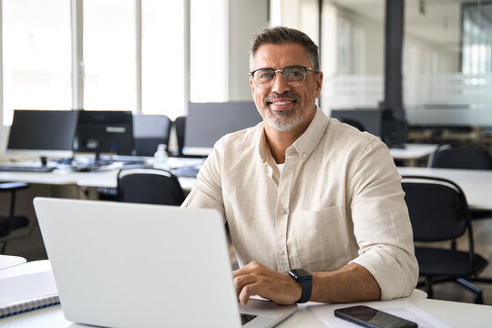 Hispanic/Latino man smiling and using the computer.