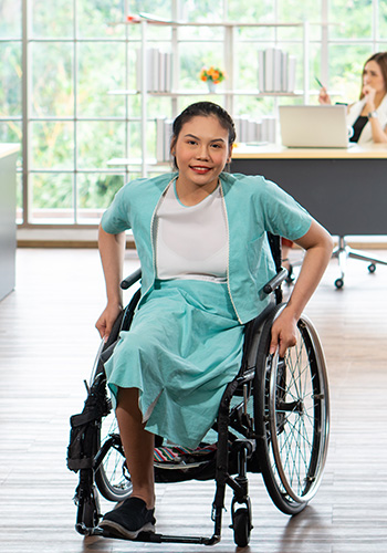 A smiling woman from the AA and NHPI community in a wheelchair.