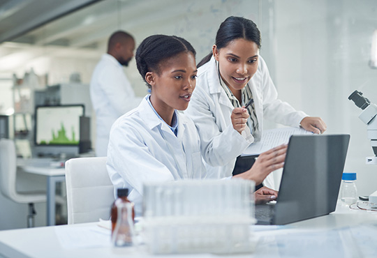 Two black scientists using a laptop in a laboratory.