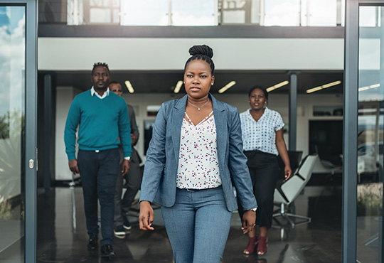 Black professionals confidentially walk out of an office.