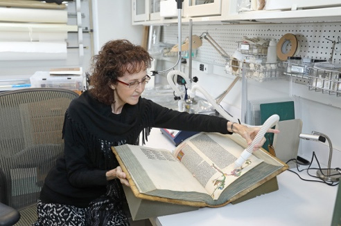 A woman holding a book in the National Library of Medicine.