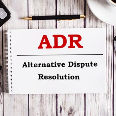 A notebook on a table reads, ADR, Alternative Dispute Resolution.
