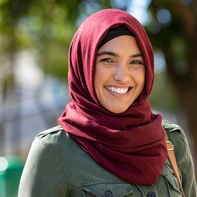 A portrait of a smiling woman wearing a headscarf or hijab.  