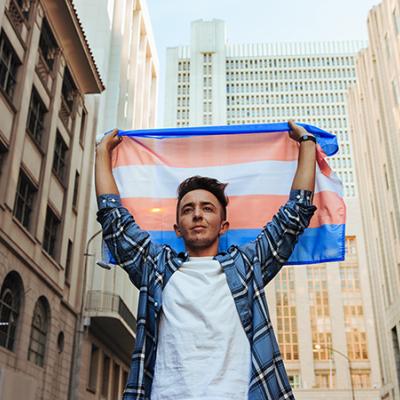 Image of a person holding the Transgender Pride flag above their head.