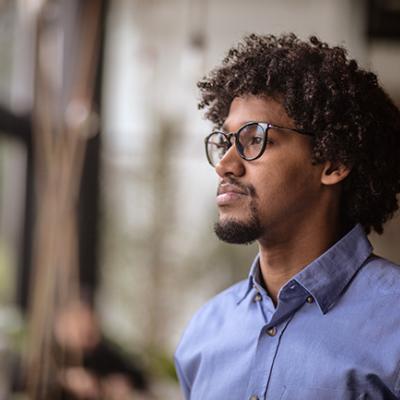 African American professional with glasses staring outside.