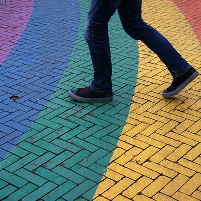 Person walking on street painted in rainbow colors.