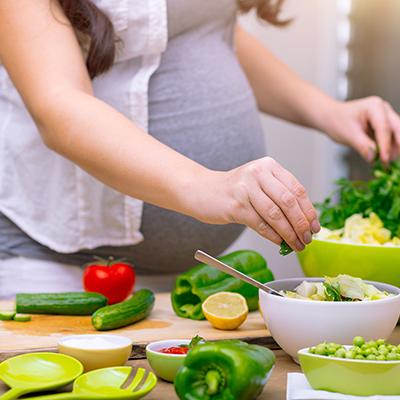 A pregnant person in a preparing food in the kitchen