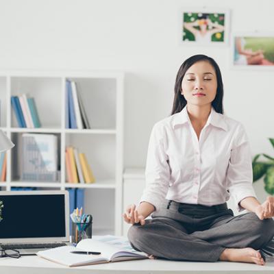 A woman sitting on her desk meditating.