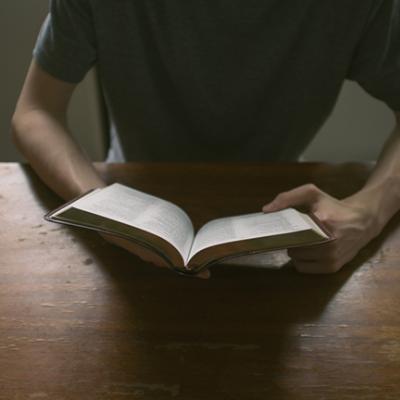 Man sitting at a desk reading the Bible.