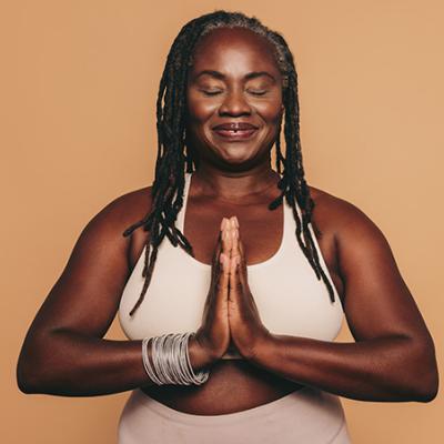 a blackA serene and smiling Black woman with dread locs in a meditative prayer pose. woman meditating